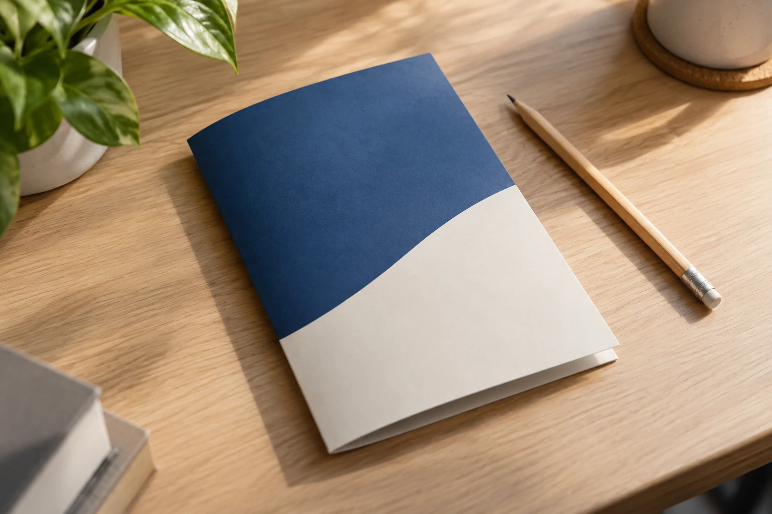 Plaquette bleue et blanche posée sur bureau en bois, crayon à côté, plante en arrière-plan